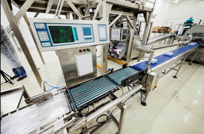 Check weigher otomatis sedang menimbang produk di atas konveyor untuk memastikan akurasi berat pada lini produksi